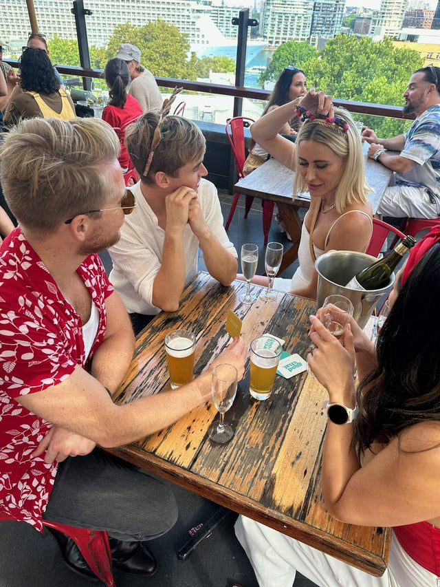 Three colleagues leaning in over Good Chat cards at a rooftop table