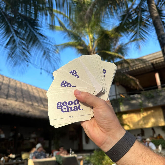 Hand fanning cream Good Chat cards against palm trees and bright blue sky