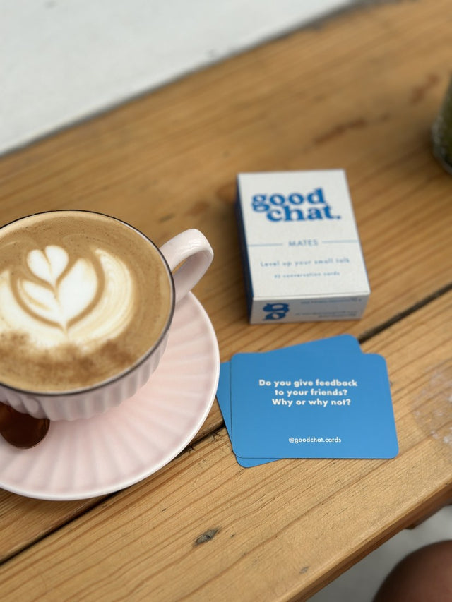 Good Chat deck and cards beside latte art on a sunny cafe table