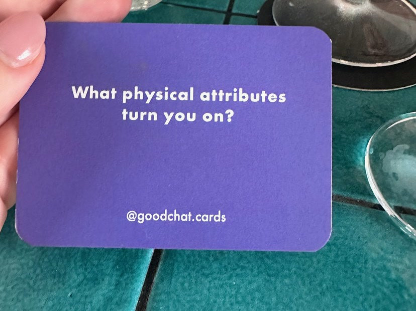Conversation card question held over a teal tiled bar table on date night