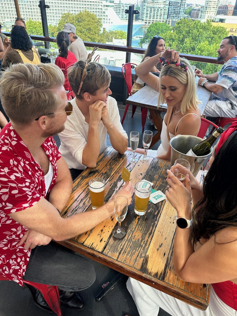 Three colleagues leaning in over Good Chat cards at a rooftop table