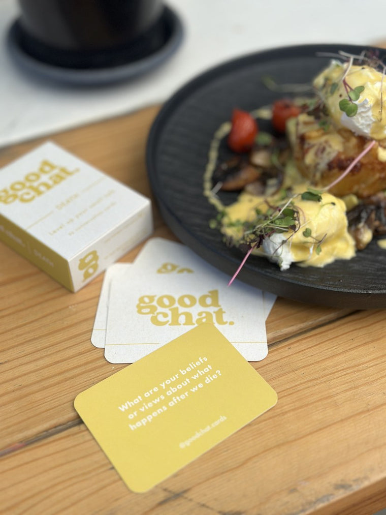 Death deck and yellow Good Chat cards beside a bright cafe brunch plate