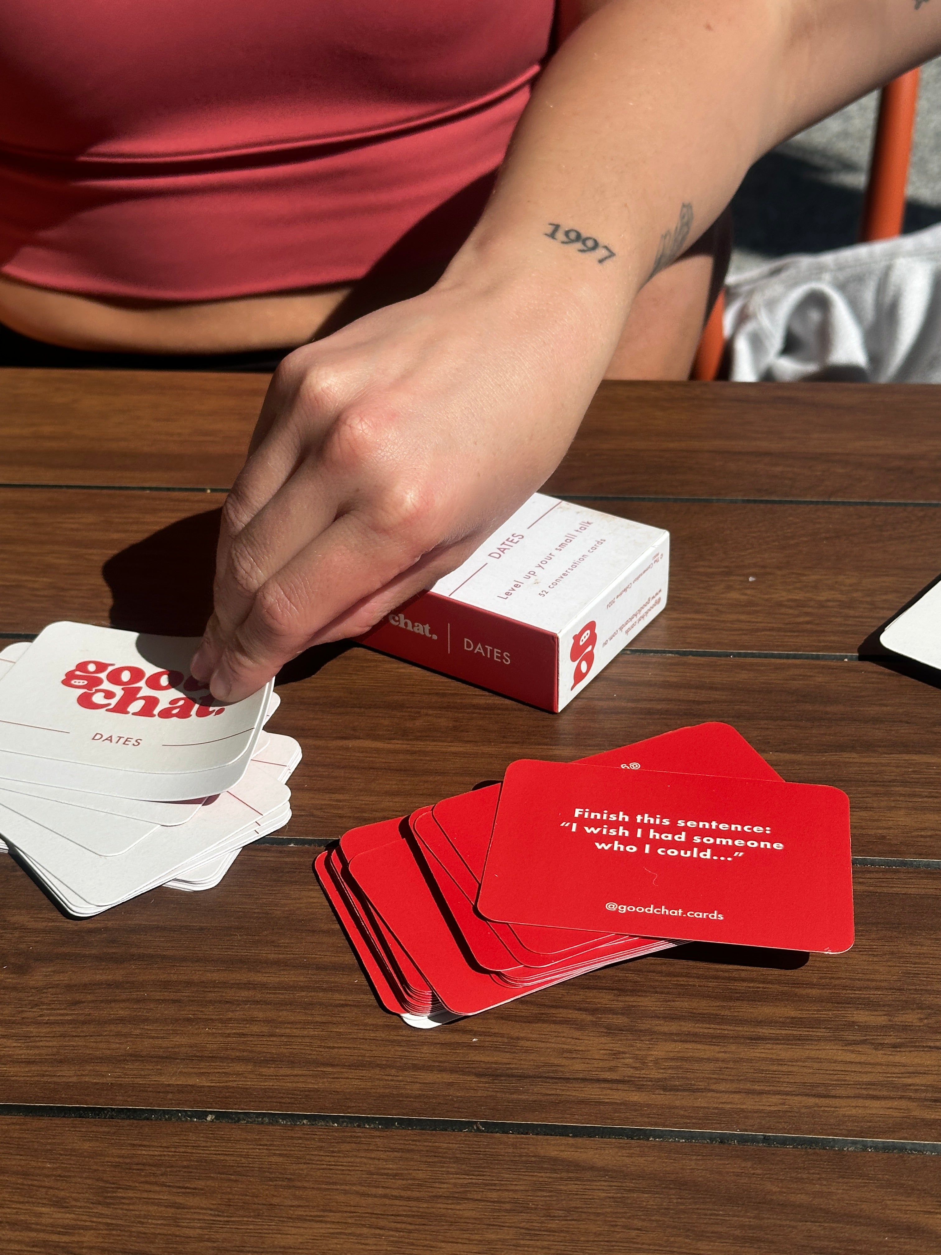 Person holding a deck of  good chat conversation cards with visible branding against a wooden background